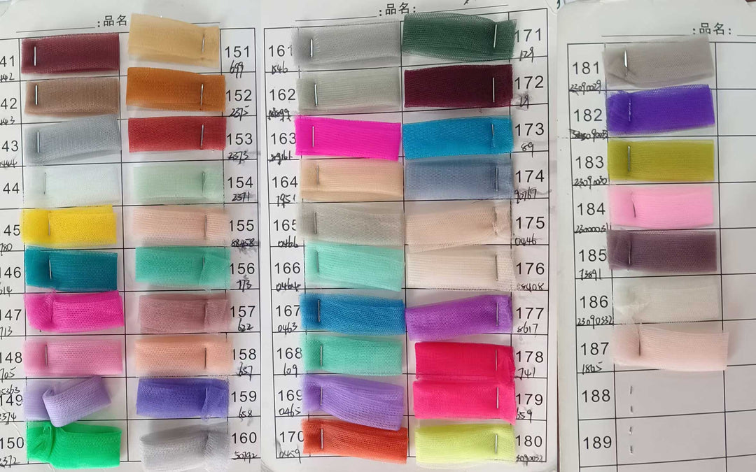 A large grid of small fabric swatches in many colors arranged on a white measurement chart with printed numbers. This is a Acaste gown color options reference image rather than a single product photo, so subject_type is Color Swatch.