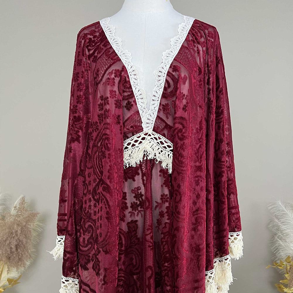 A Red wine,A bacche dress with a velvet cape and tassel displayed on a mannequin.