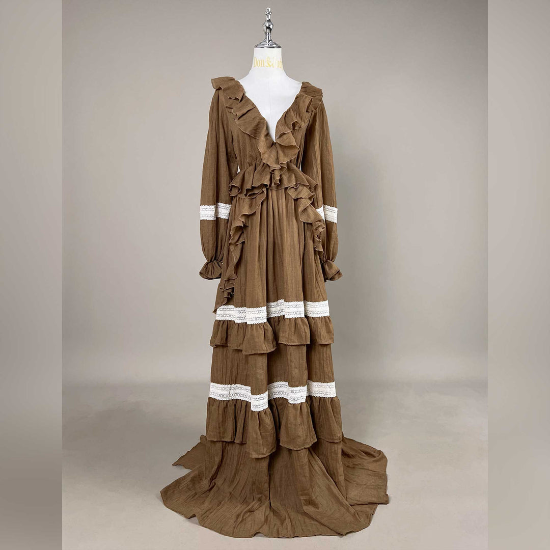 A Cassandra coffee long-sleeve tiered dress on a mannequin facing forward, train on the floor, gray background.