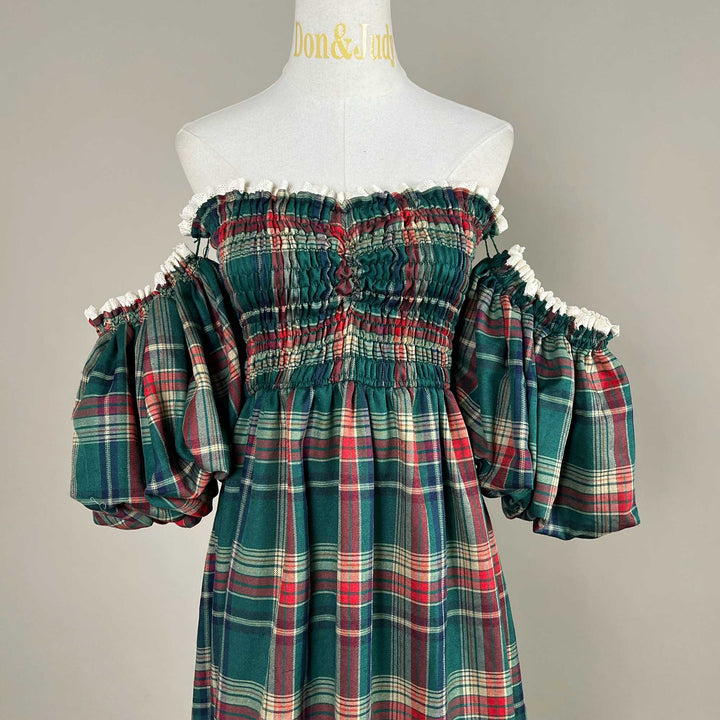 A bodice close-up of the Catubri plaid dress, showing the white lace neckline, smocked bodice and puff sleeves on both sides.