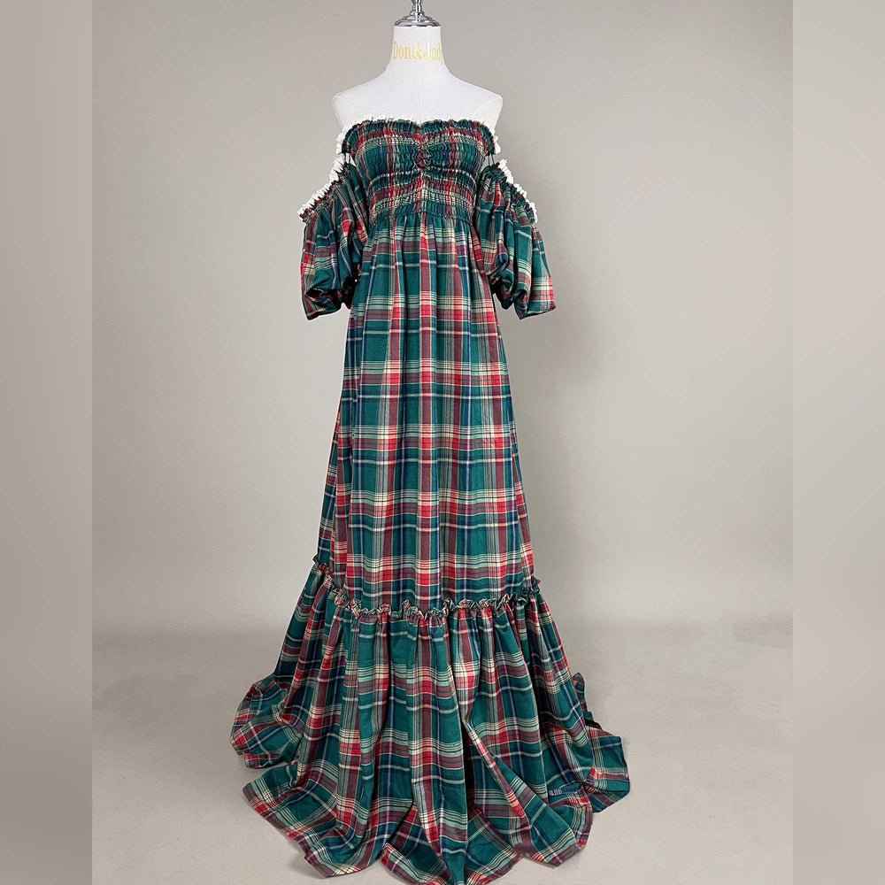 A Catubri green-red plaid off-shoulder maxi dress on a mannequin facing forward, with a ruffled lower tier and train on the floor, gray background.