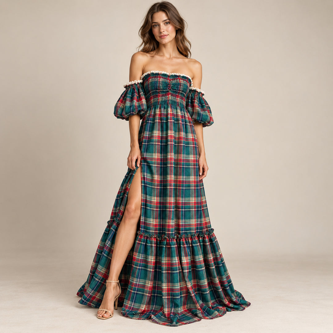 A woman in a Catubri green-red plaid off-shoulder maxi dress with puff sleeves, a side slit and a ruffled hem, wearing heeled sandals against a light backdrop.