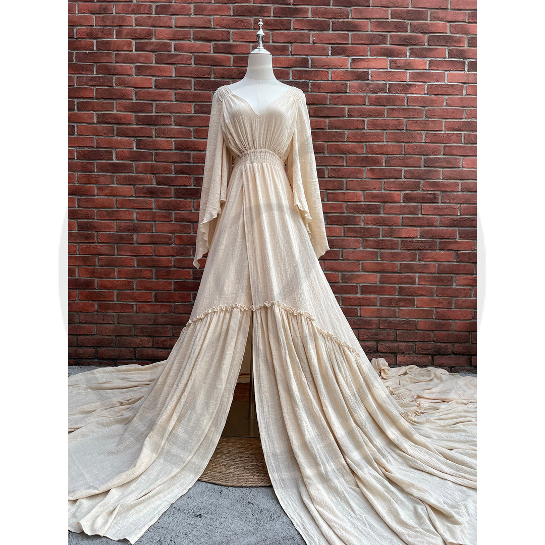 A Daphne begie long-sleeved V-neck gown is displayed on a mannequin.The dress features a high front slit and its hem and train are spread out on the wooden floor.

