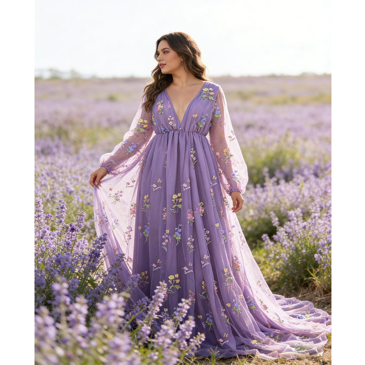 A woman stands in a flower field wearing a Dike purple V-neck tulle floral embroidered gown. 