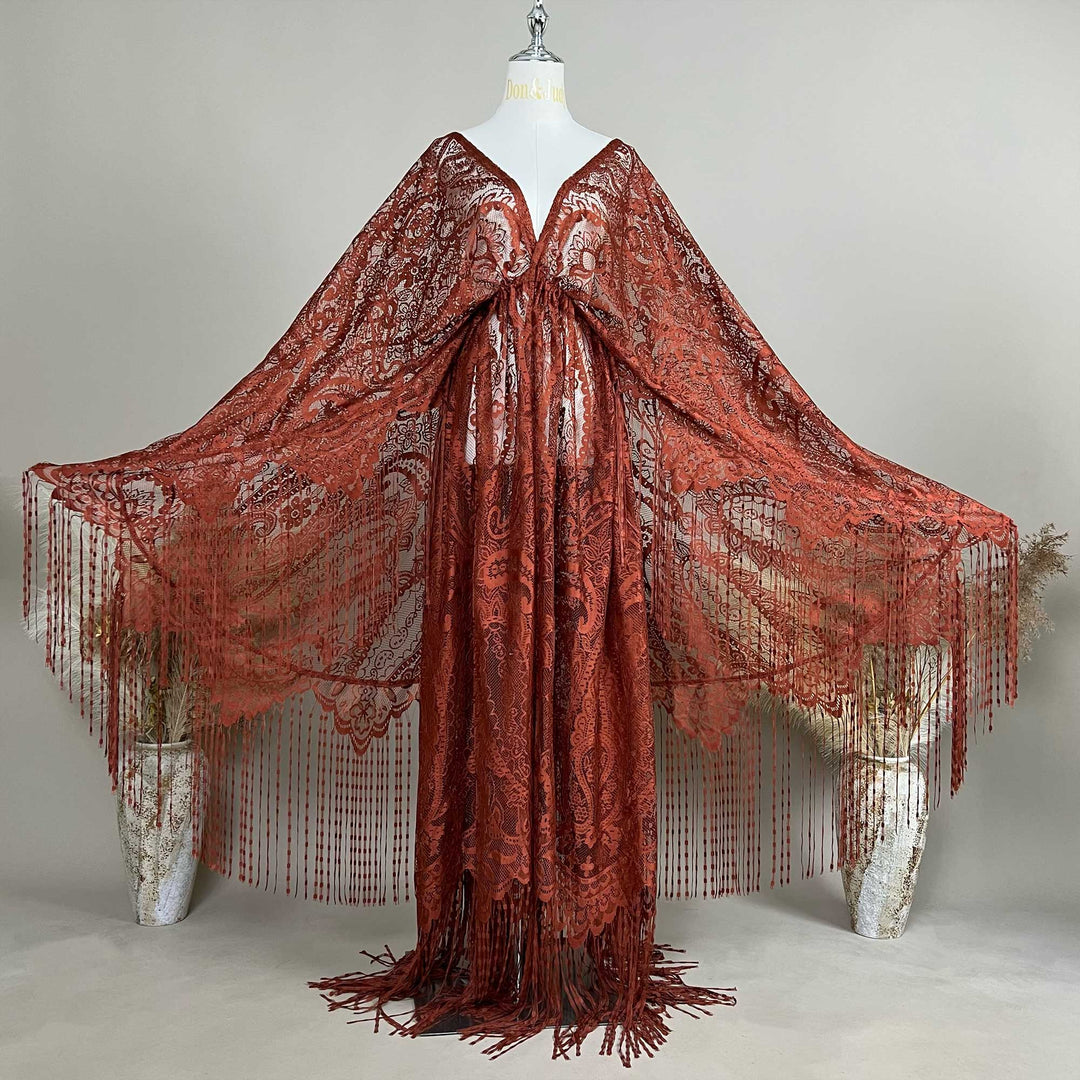 A mannequin displays a rust lace fringe cape with a deep V-neck and wide sleeves; the fabric features an openwork pattern.