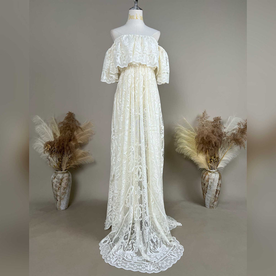 A mannequin displays a beige off-shoulder lace gown with ruffled sleeves and a train.