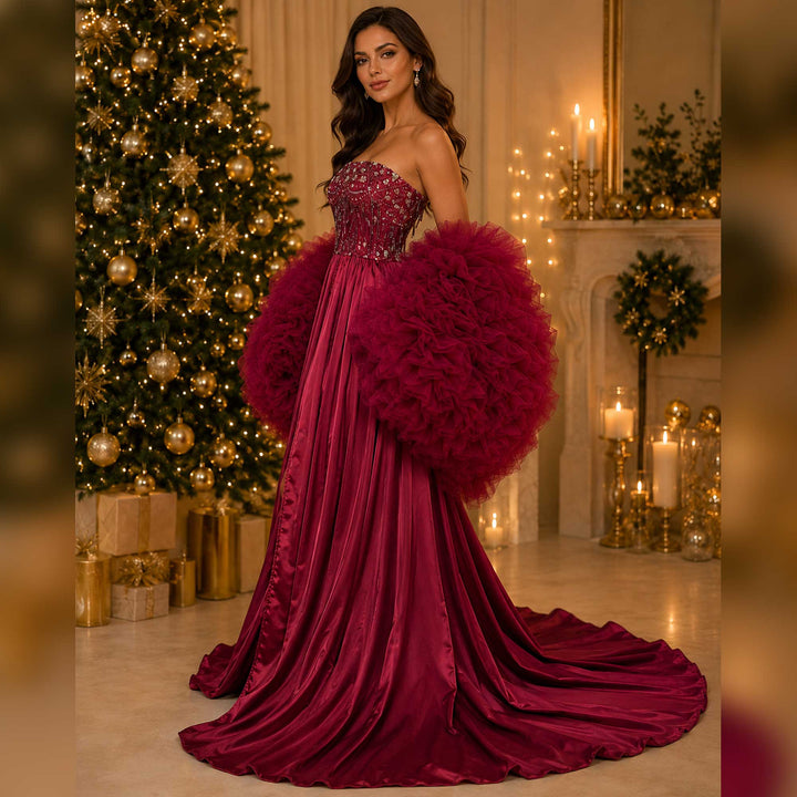 A woman in a red Luna strapless gown and matching feathered shawl stands indoors.