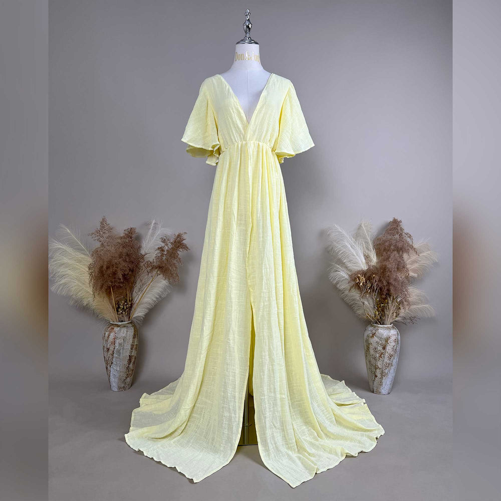 A mannequin displays a yellow V-neck short-sleeve gown with a high-waist pleat and train; the fabric has a textured finish.