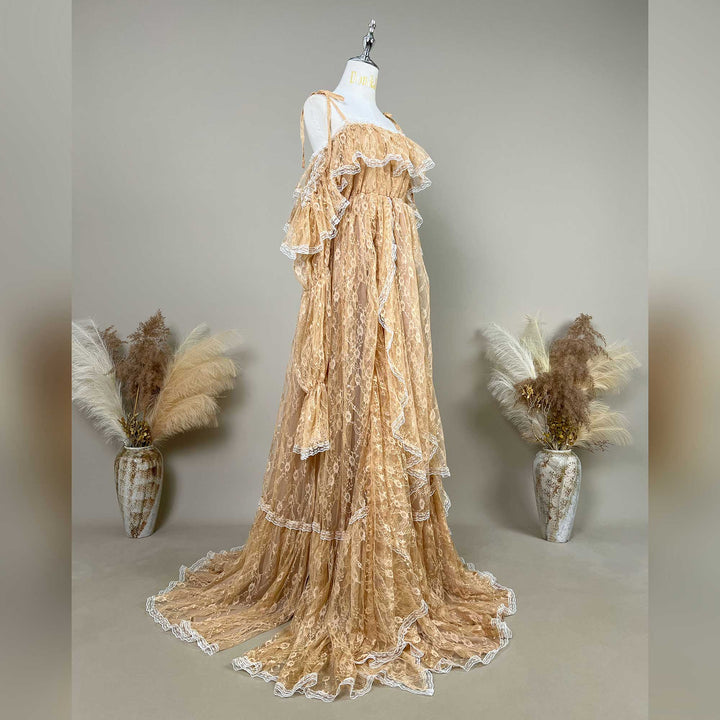 A khaki lace maternity gown with cascading ruffles and a sweeping train is displayed on a mannequin against a neutral gray background.