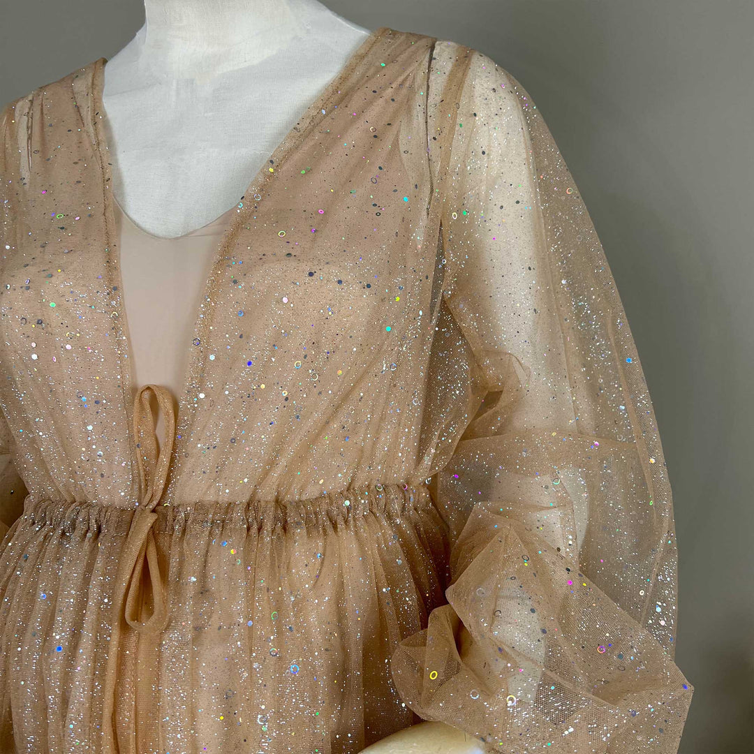 A mannequin displays the upper body of a khaki sequined V-neck robe with a tie waist and lantern sleeves; the fabric is transparent tulle.