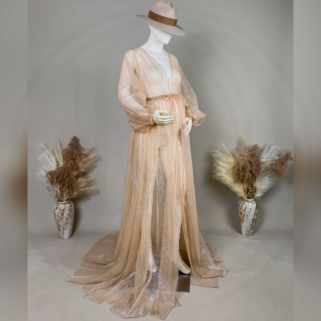 A hat-wearing pregnant mannequin displays a khaki sequined robe with a tie waist and lantern sleeves; the dress features a split train.