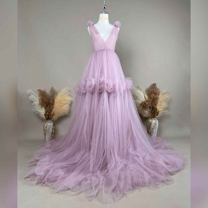 A purple Mila tulle gown is displayed on a mannequin with floral details on the shoulders, waist, and neckline. 