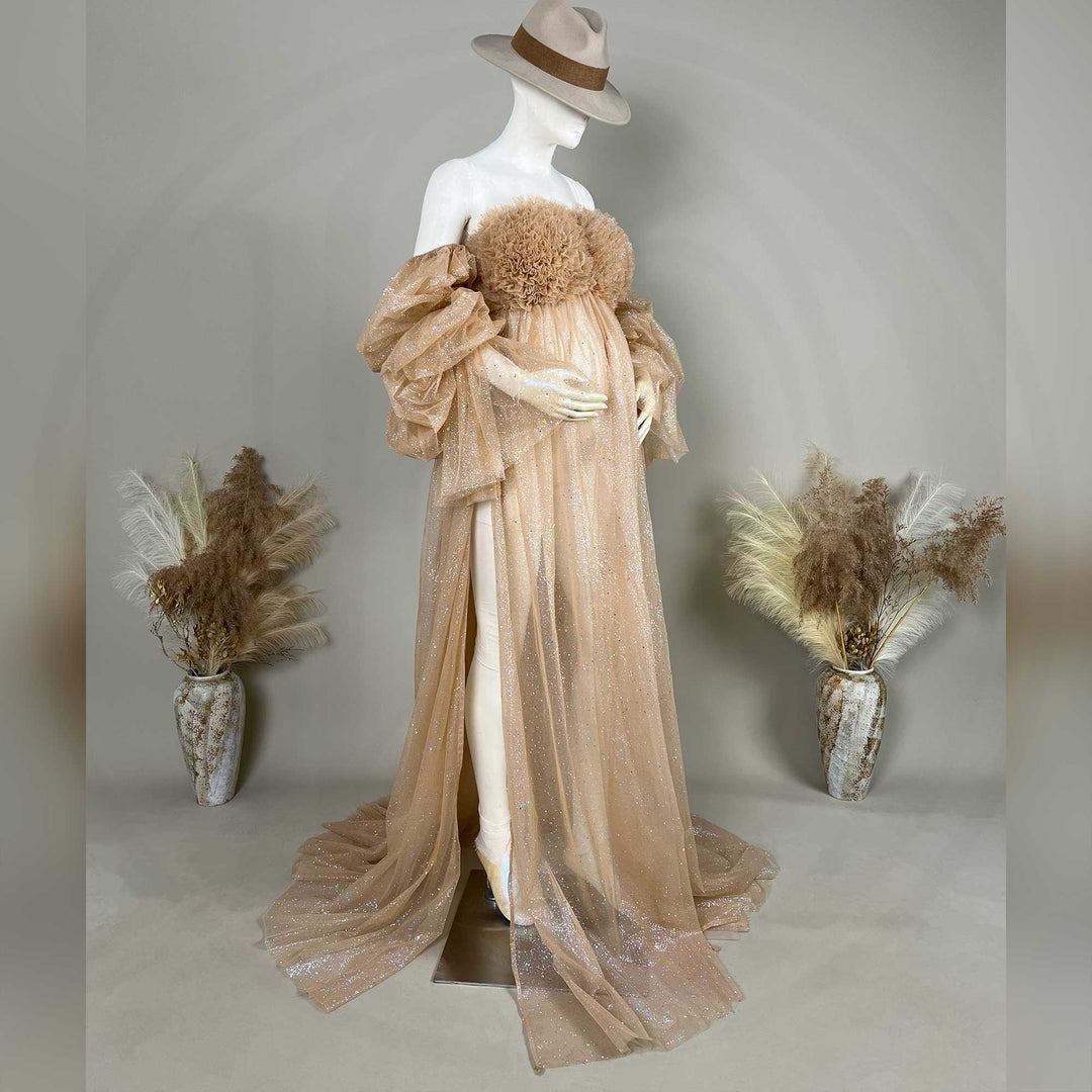A hat-wearing mannequin displays a champagne sequined off-shoulder maternity gown with feather chest decor and a split train.