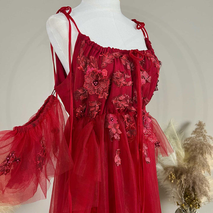 Close-up detail of the red floral embroidered off-shoulder tiered ruffle maternity photography dress, highlighting the front neckline and gathered waist design details.