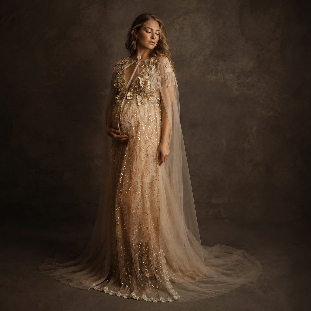 A pregnant model displays a gold sequined gown with a tulle cape, featuring 3D floral decorations and a train skirt.
