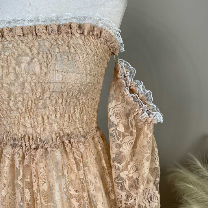 A close-up of the khaki lace dress bodice and sleeves is displayed on a mannequin, featuring horizontal shirring, rose patterns, and white lace ruffles.