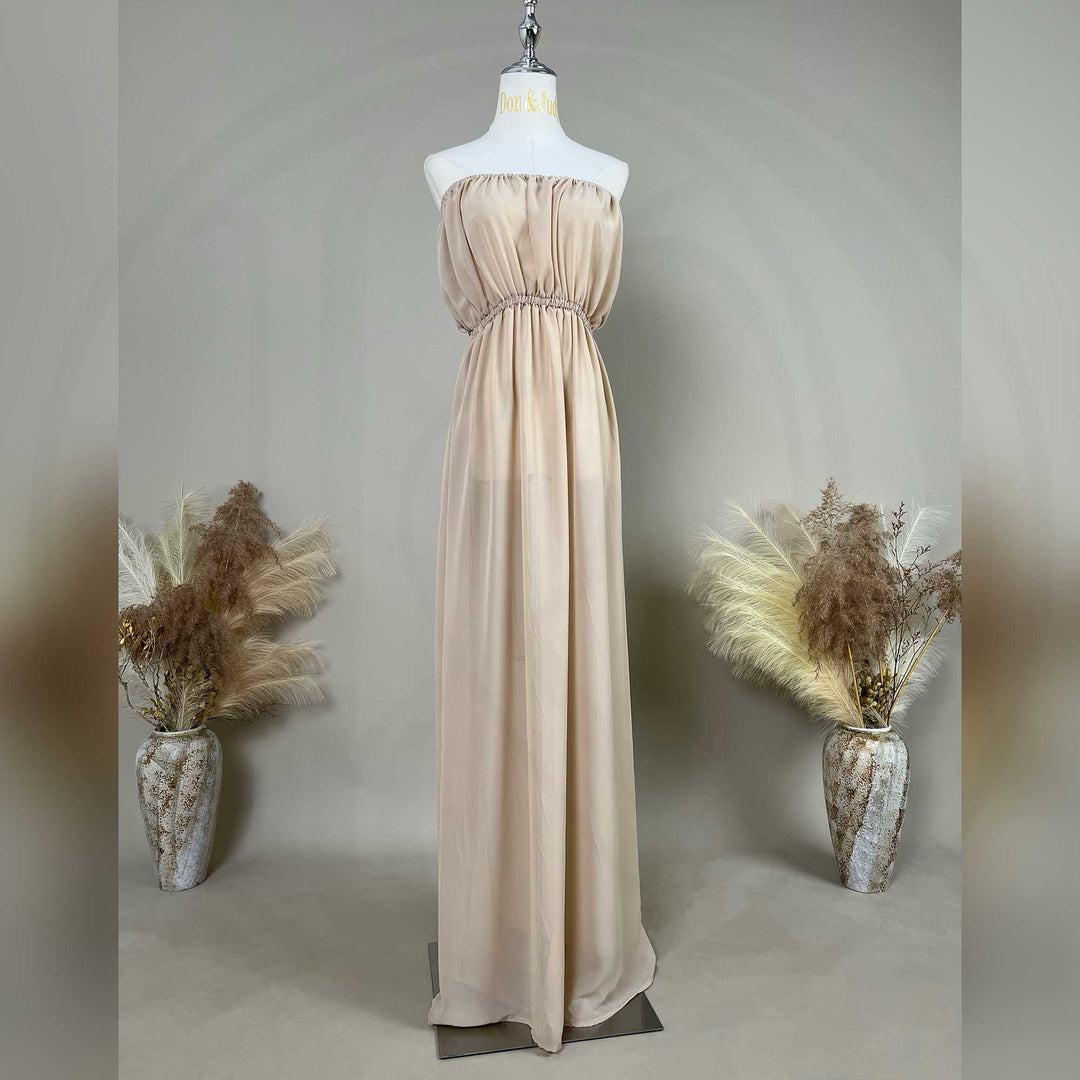 A chiffon strapless gown is displayed on a mannequin, featuring a ruched bodice, rhinestone waistline, and draped skirt.