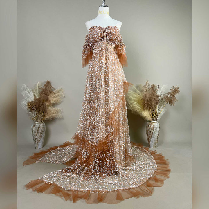 A Khaki Tyche gown with embroidery is displayed on a mannequin; the dress features a train and a ruffled hem structure.