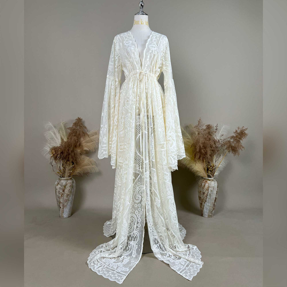 A beige lace ,Zephyra dress with long bell sleeves and a V-neckline, displayed on a mannequin. The robe features a tie waist, an open front, and a floor-length train with scalloped edges.